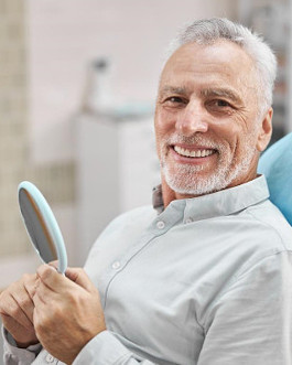 A senior adult white male smiling broadly after undergoing his dental procedure.